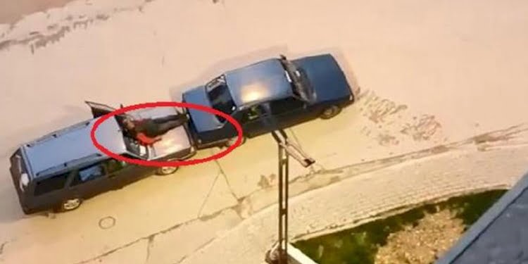 Otomobilin kaputuna oturup ayaklarıyla öndeki aracı itti