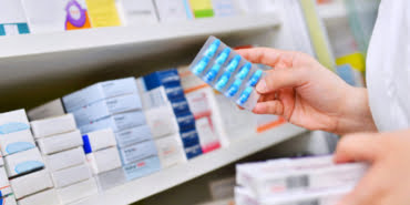pharmacist-holding-medicine-box-capsule-pack-pharmacy-drugstore_67340-24