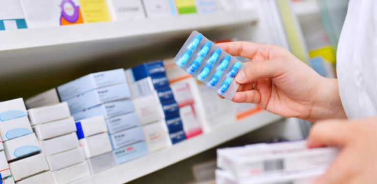 pharmacist-holding-medicine-box-capsule-pack-pharmacy-drugstore_67340-24