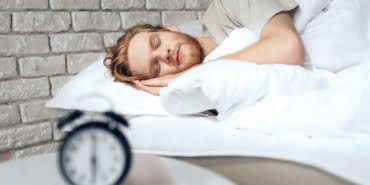 red-haired-young-man-sleeps-bedroom-near-alarm-clock_99043-5301