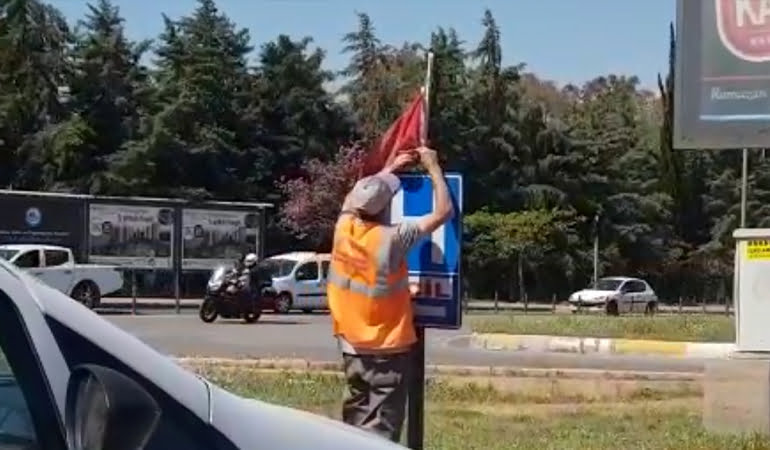 Yerde bulduğu Türk bayrağını temizleyip tabelaya astı