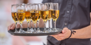 Waitor holding a serving tray full of drinks in champagne glasses.